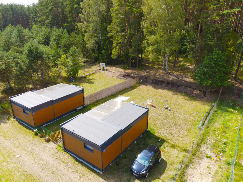 Die beiden Häuser von Kwiat Jabłonki aus der Vogelperspektive, umgeben von Kiefernwald