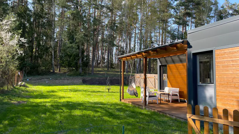 Terrasse eines Hauses im Frühling, blühende Bäume und Kiefernwald im Hintergrund